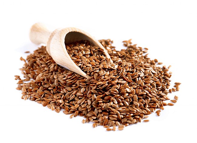 Горка семян льняных сверху них маленький красивый совочек с семенами